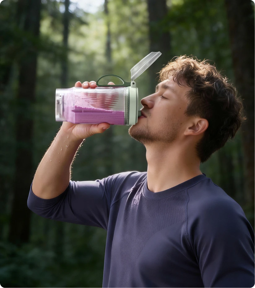 Utilisateur buvant un smoothie avec le bol portable Dreame Portable Blender lors d'une randonnée en forêt