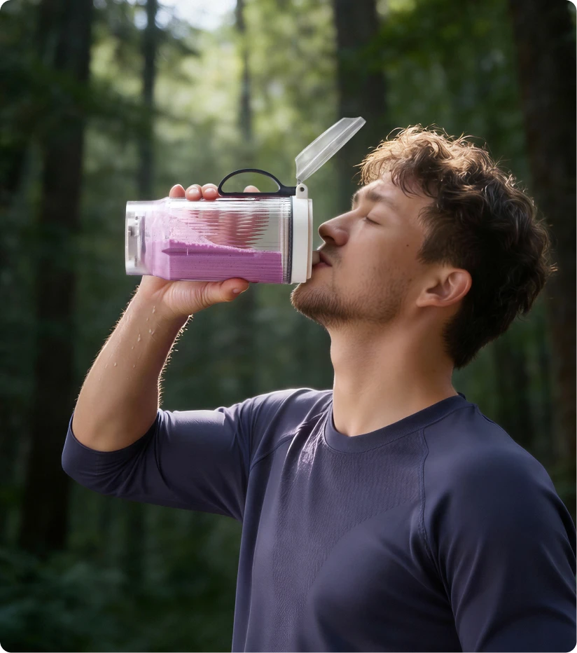 Utilisateur buvant un smoothie avec le bol portable Dreame Portable Blender lors d'une randonnée en forêt
