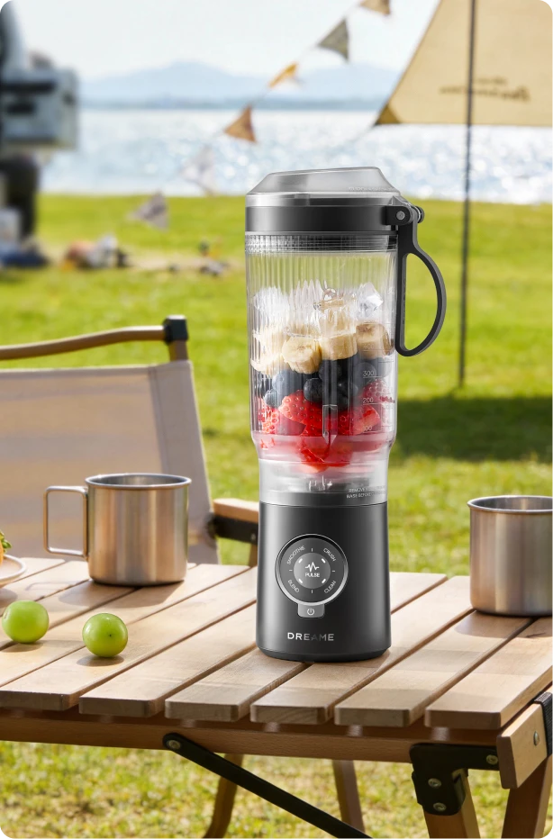 Dreame Portable Blender design sans fil sur une table de pique nique préparant des boissons aux fruits en extérieur
