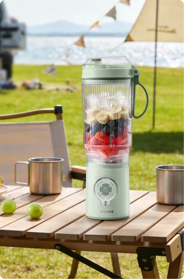 Dreame Portable Blender design sans fil sur une table de pique nique préparant des boissons aux fruits en extérieur